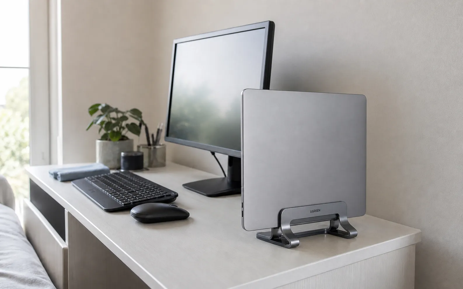 UGREEN grey dual-slot vertical laptop stand on a compact bedroom desk